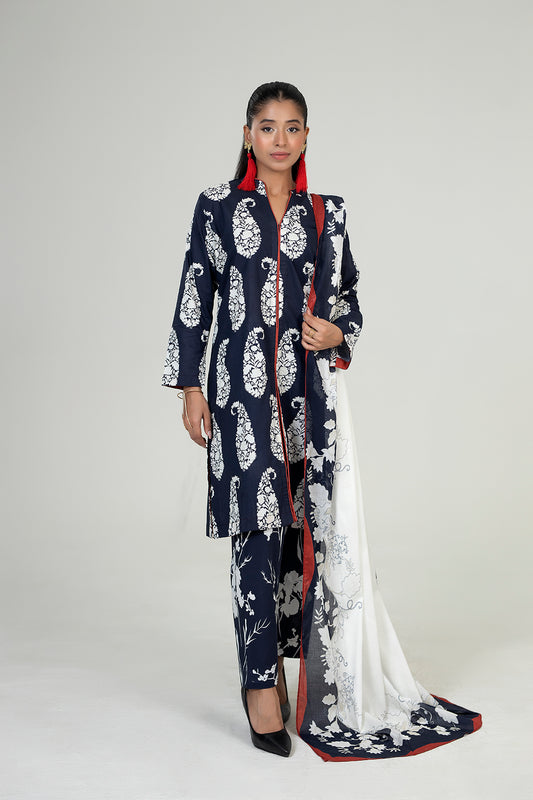 Woman wearing a navy blue and white patterned outfit with a white scarf on a gray background