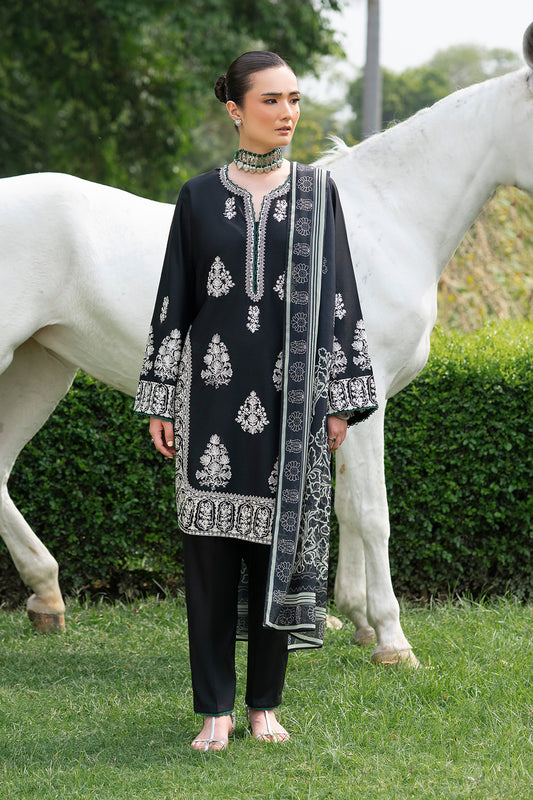 A woman standing beside a white horse, wearing a black outfit with white embroidery and a digital printed silk dupatta.