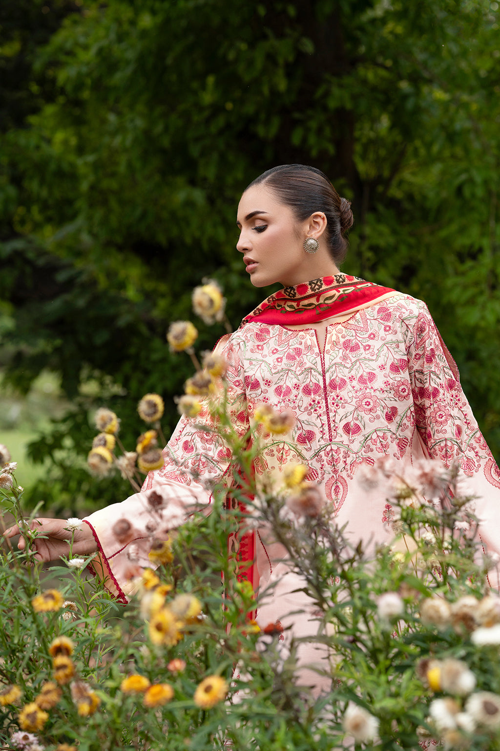 Woman in a patterned dress among flowers and greenery