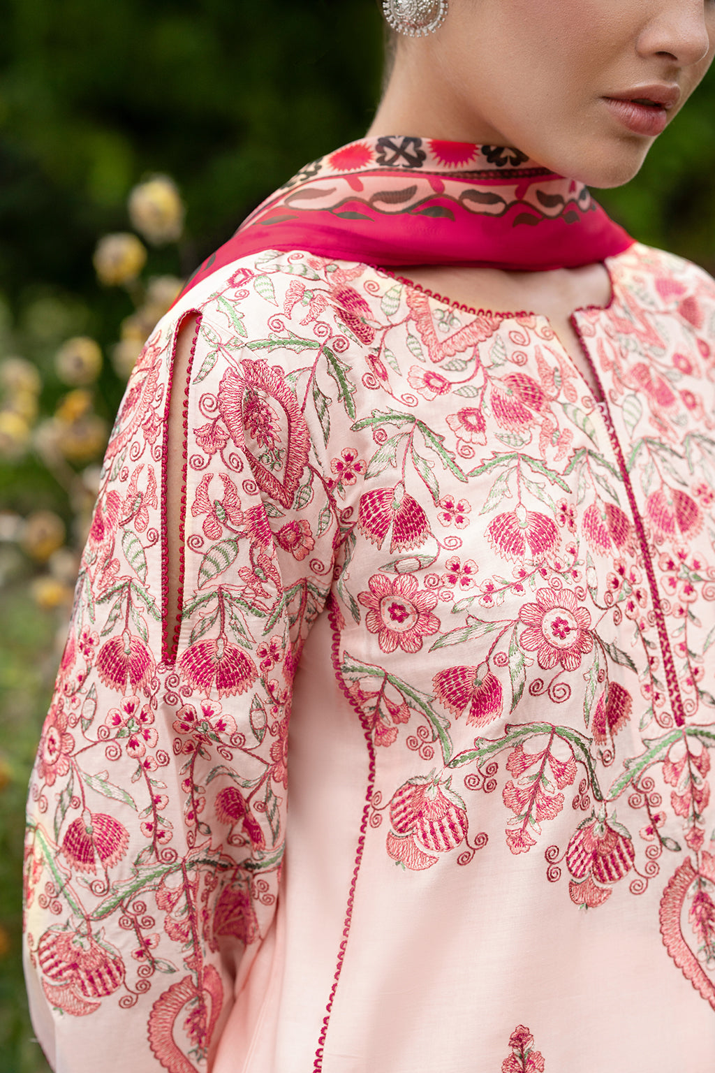Close-up of a garment with floral embroidery and a pink neckline.