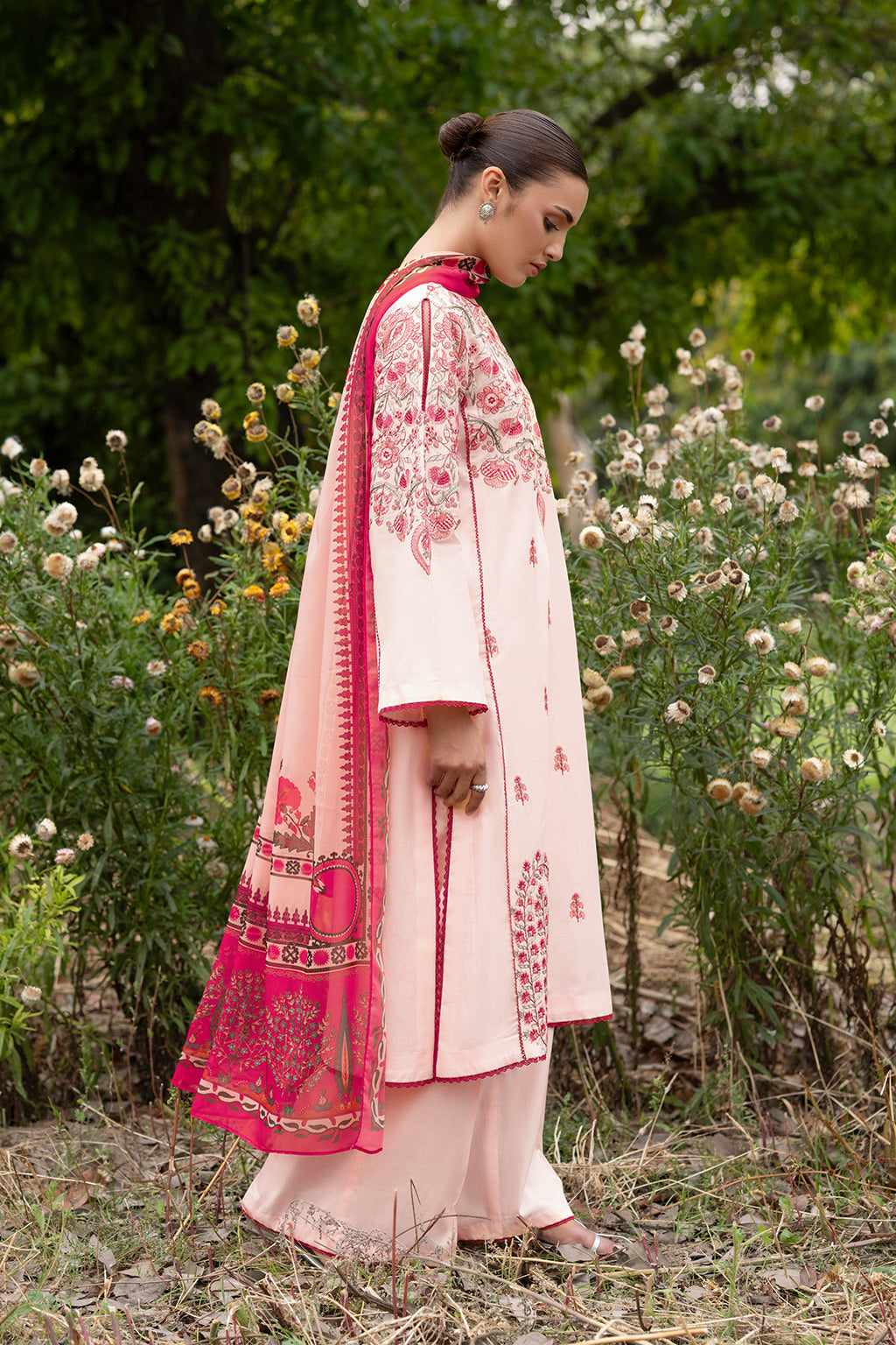 Woman in a traditional outfit standing in a garden.