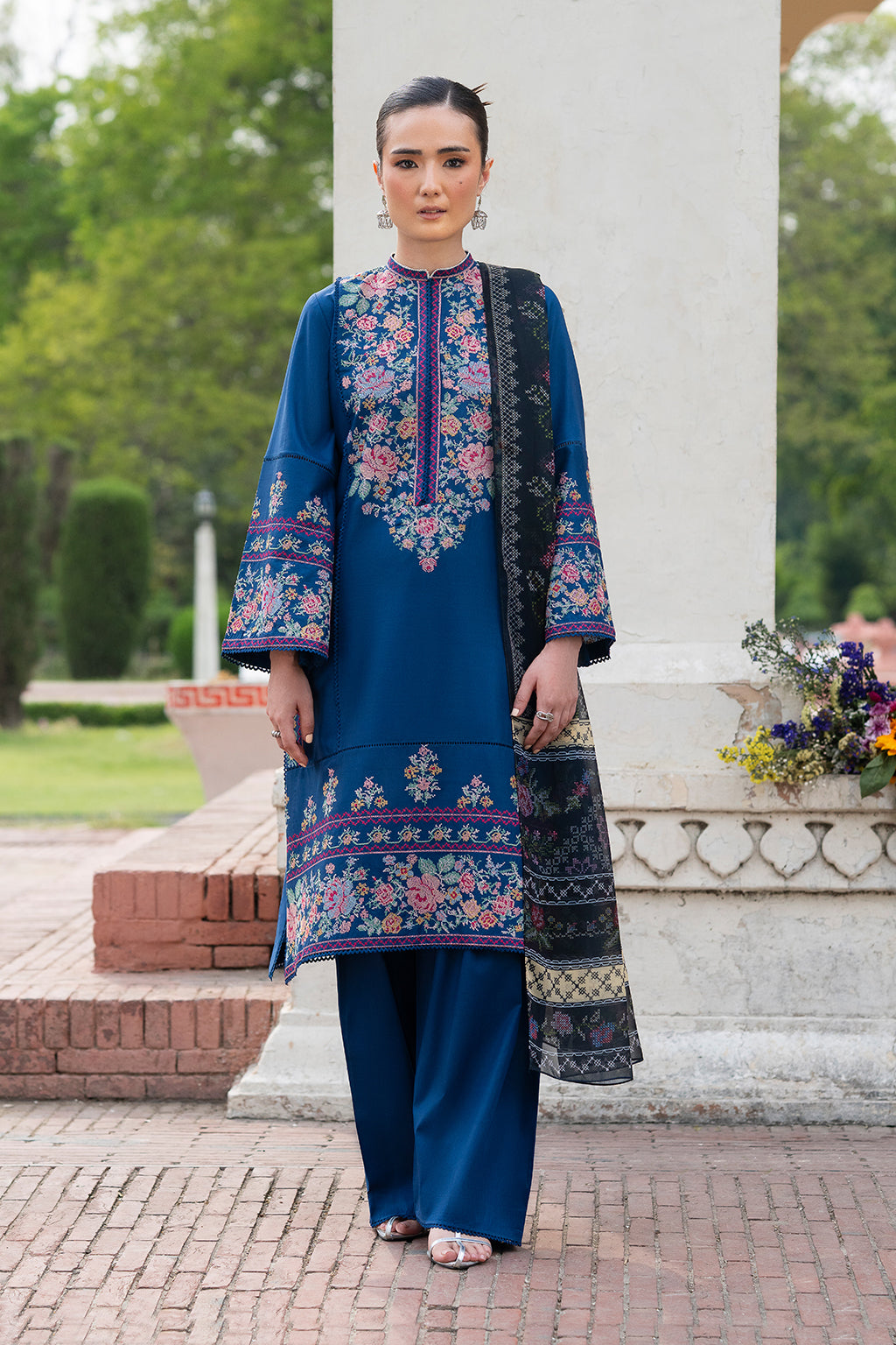 A woman wearing a traditional deep blue ensemble with intricate embroidery and a digital printed silk dupatta.