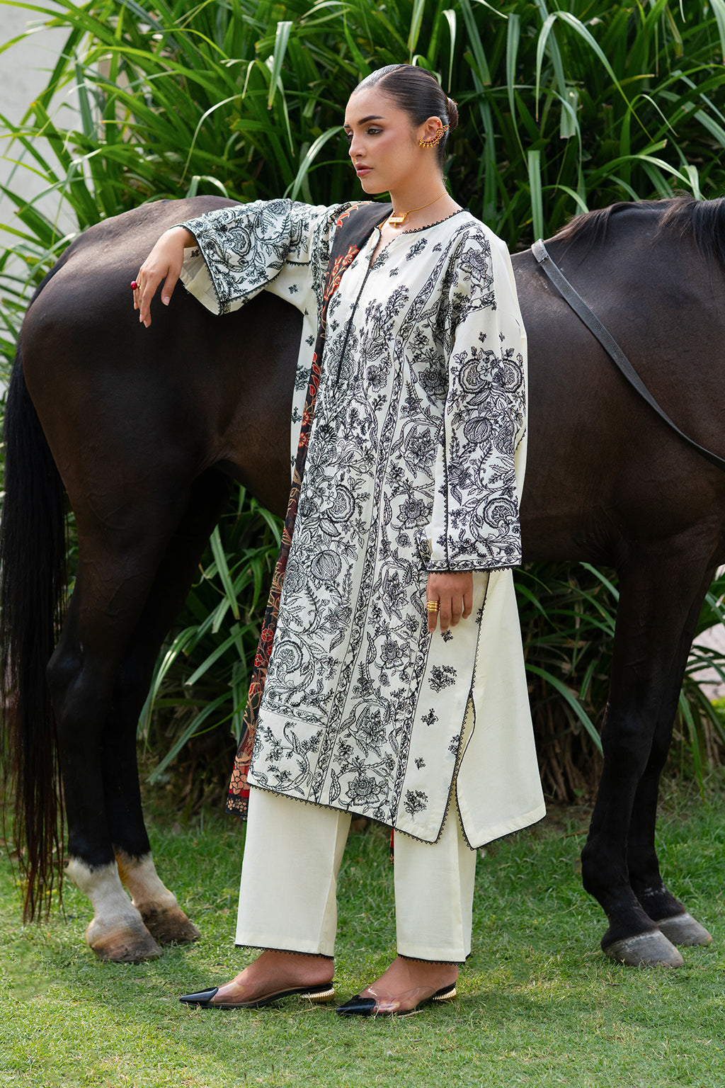 Woman in traditional outfit posing with a horse in a garden setting