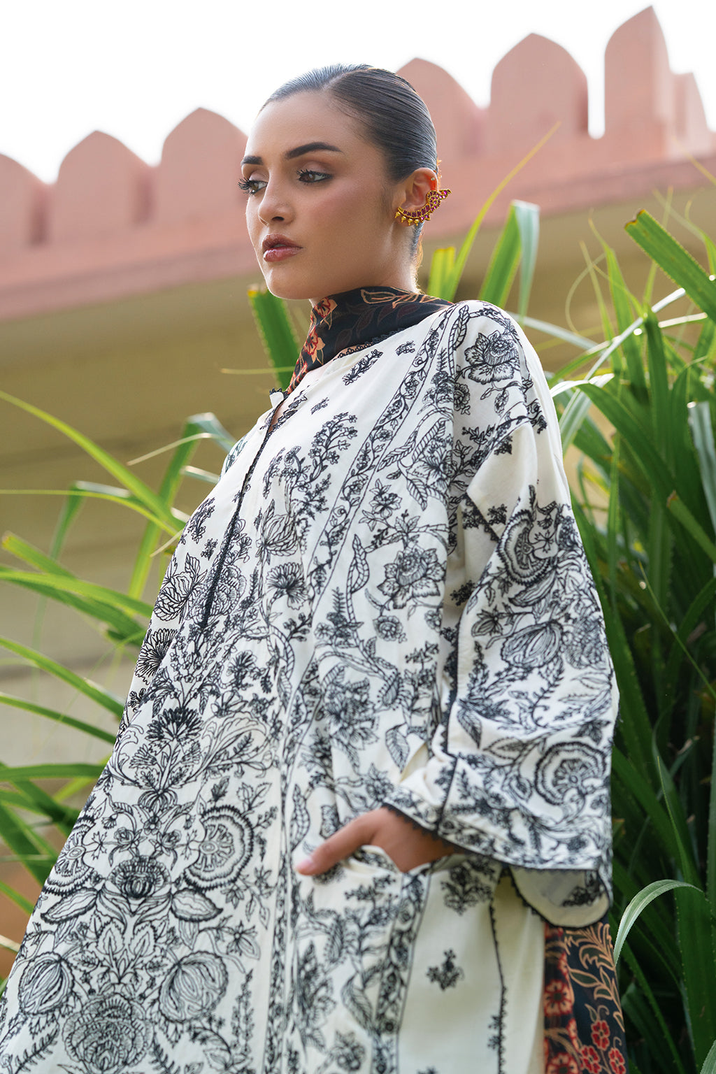 Woman in a patterned dress with plants and architecture in the background