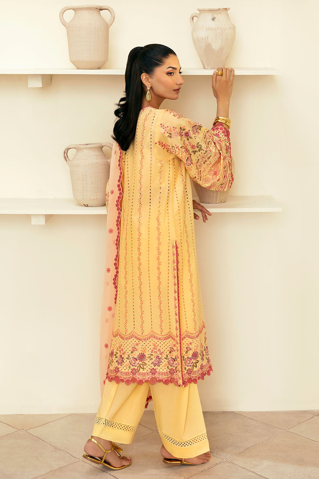woman wearing a traditional yellow dress with intricate embroidery and wearing dupatta back side of shirt