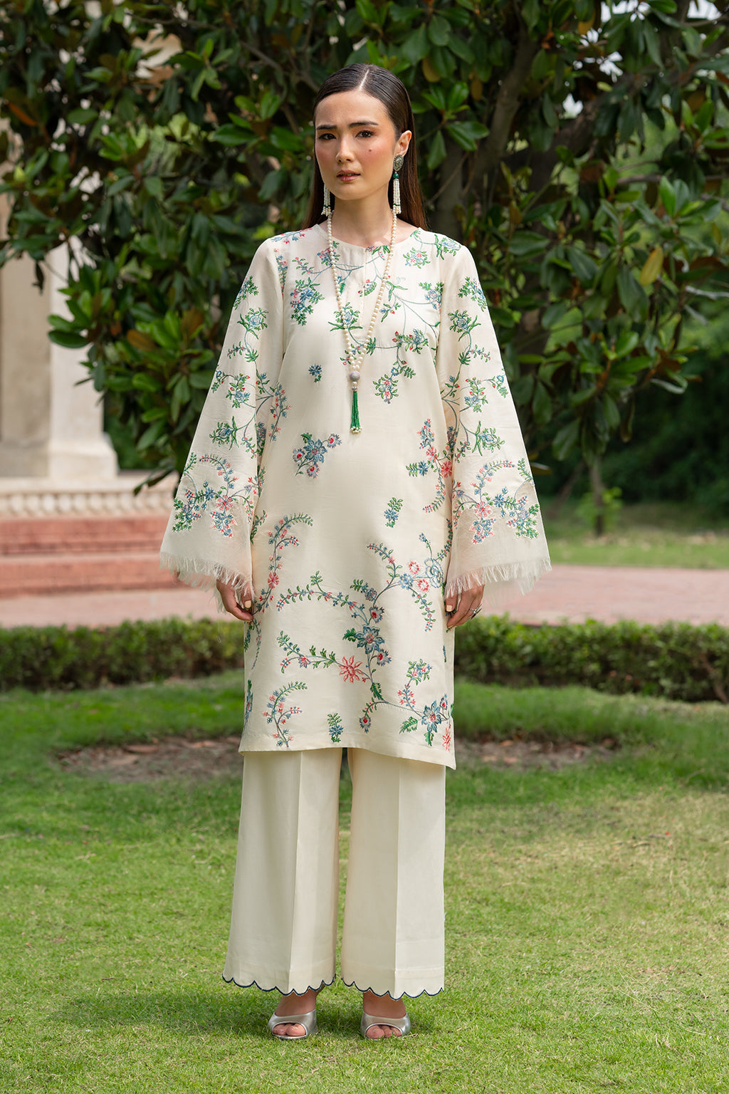 Person wearing a floral embroidered outfit on a grassy background.