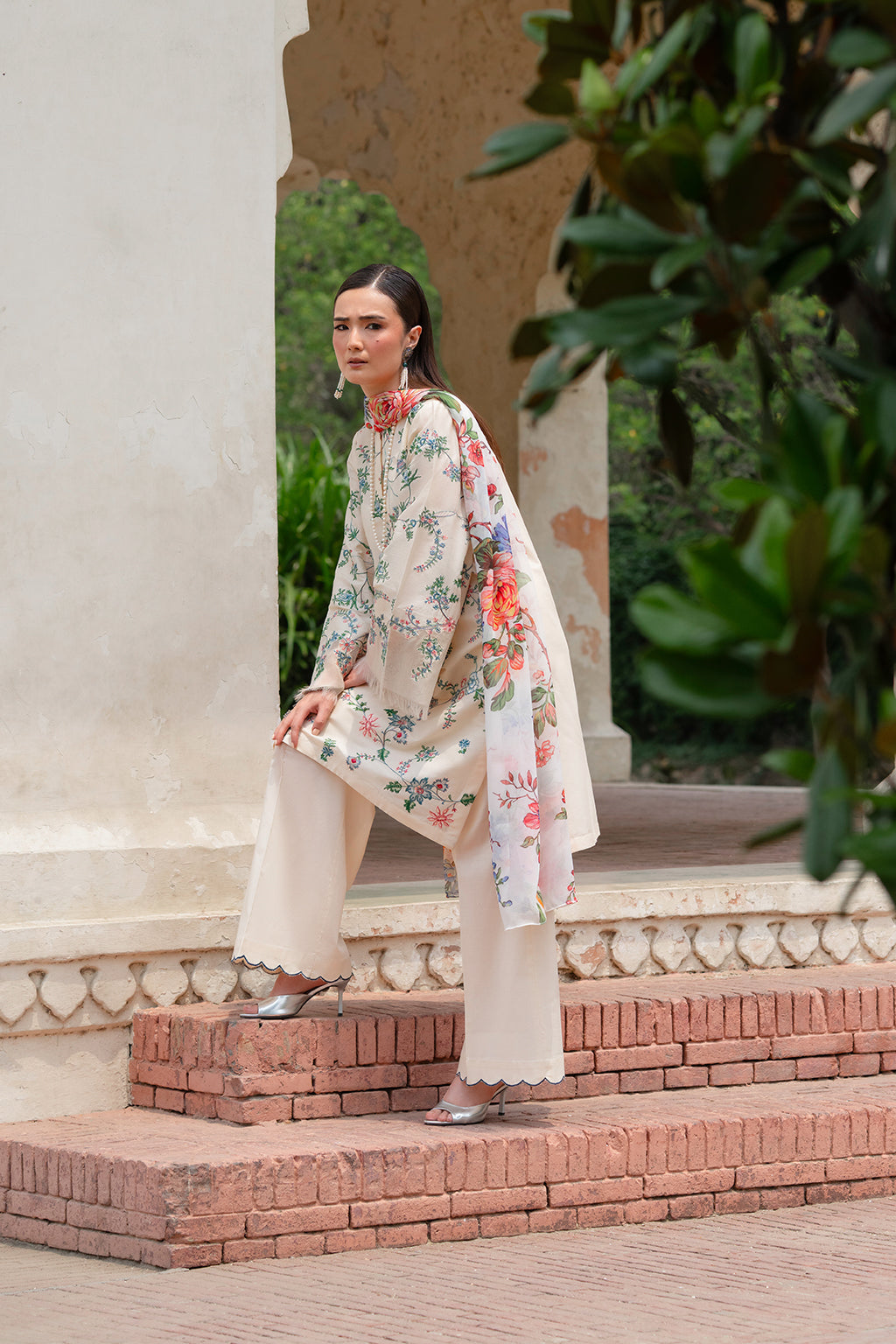 Woman in floral dress and sandals sitting on steps in a garden setting