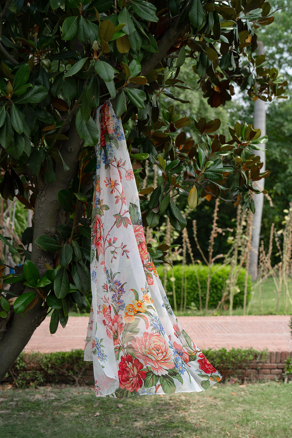 Floral dress hanging from a tree in a garden setting