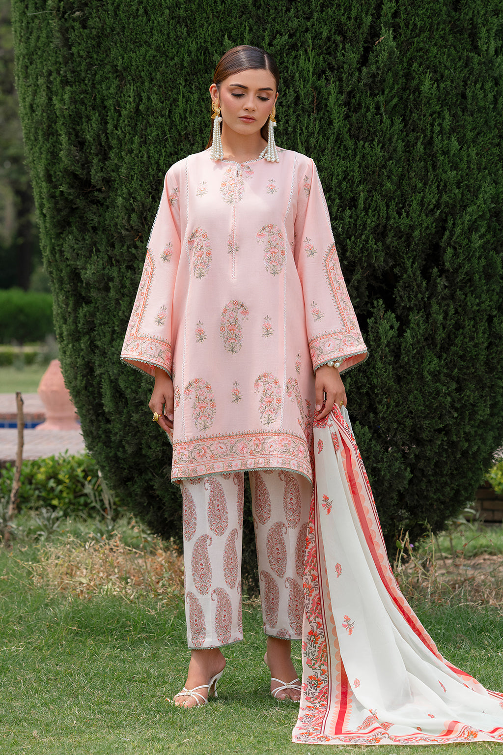 Woman in pink embroidered outfit with matching dupatta in a garden setting