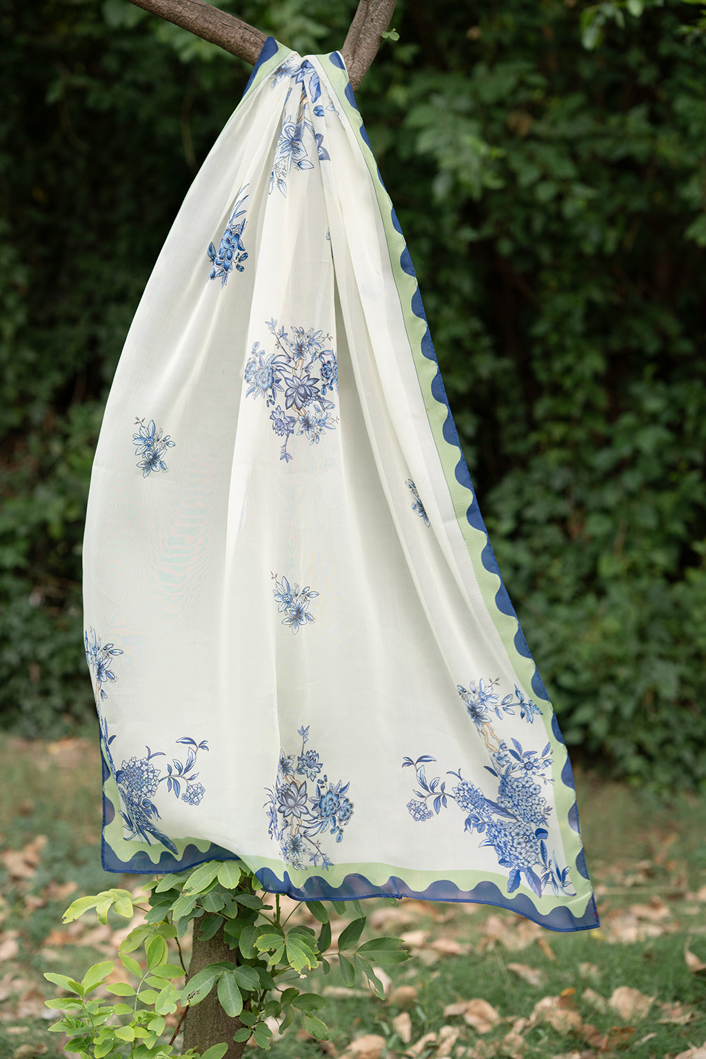White fabric with blue floral patterns draped over a branch.