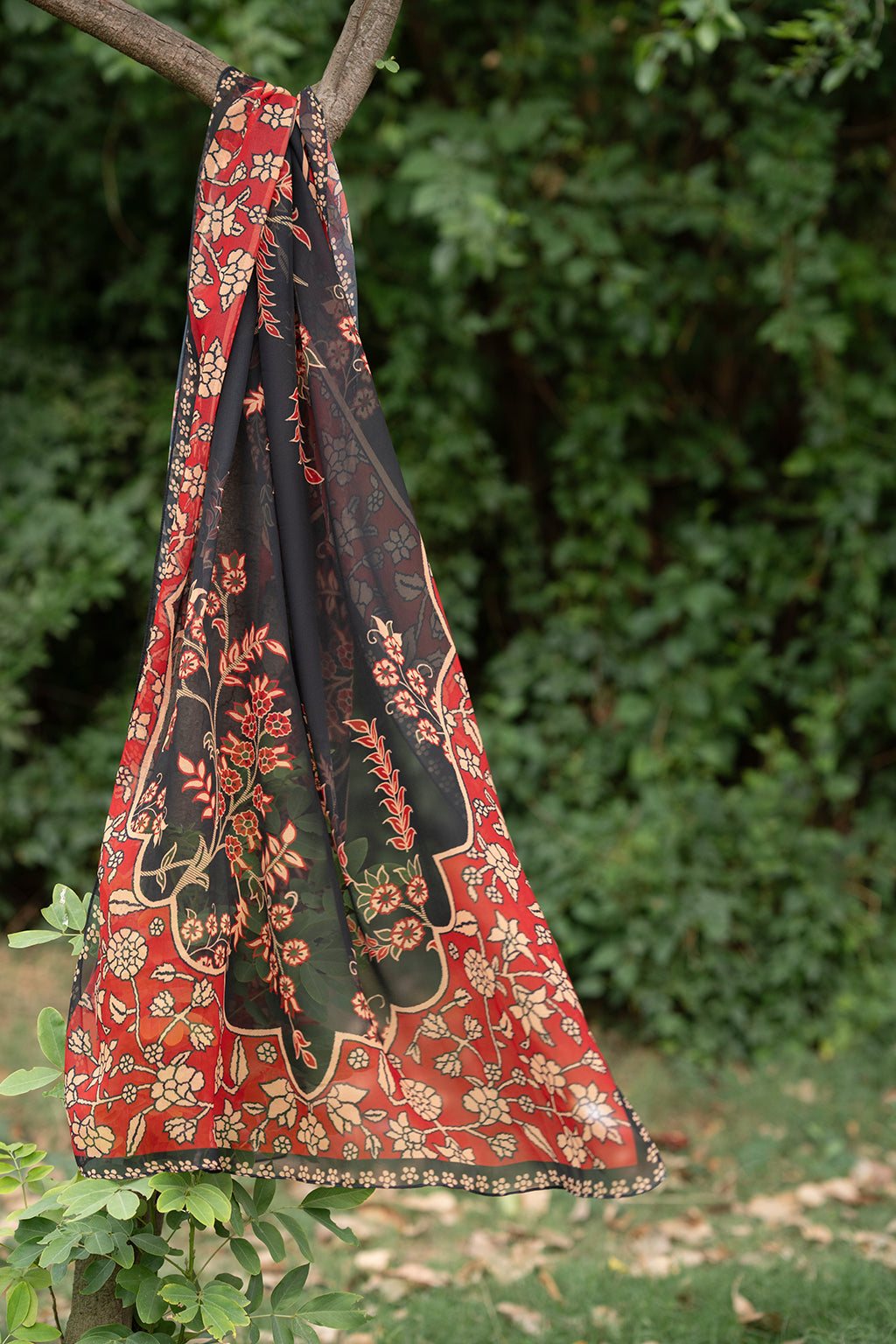 Decorative fabric with floral patterns hanging from a branch.